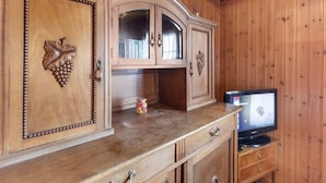 Un mueble de madera con televisor integrado, cajones y un juguete pequeño sobre la encimera.