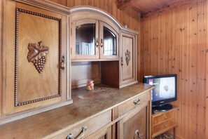 A wooden cabinet with a built-in television, drawers, and a small toy on the countertop.