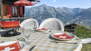 Mesa para cuatro con vista a la montaña, un paraguas rojo de Coca-Cola y una servilleta con la bandera suiza roja.