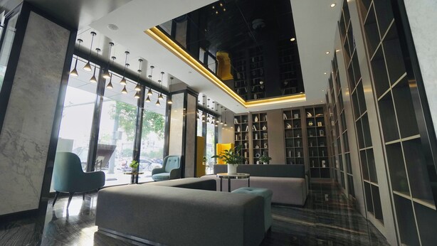 A modern lobby with seating areas, a large bookshelf, and a skylight. - Paco Hotel Guangzhou Baiyun Airport Liantang Metro (Guangzhou)