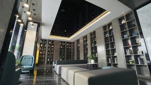 A modern library with bookshelves, seating areas, and a skylight. - Paco Hotel Guangzhou Baiyun Airport Liantang Metro (Guangzhou)
