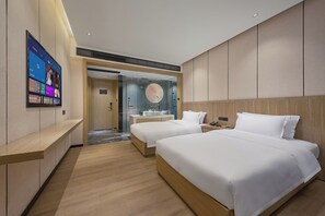 A hotel room with two beds, a bathroom, and a TV displaying a program.