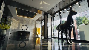 A modern lobby with a large glass window, a decorative horse statue, and a marble floor. - Paco Hotel Guangzhou Baiyun Airport Liantang Metro (Guangzhou)
