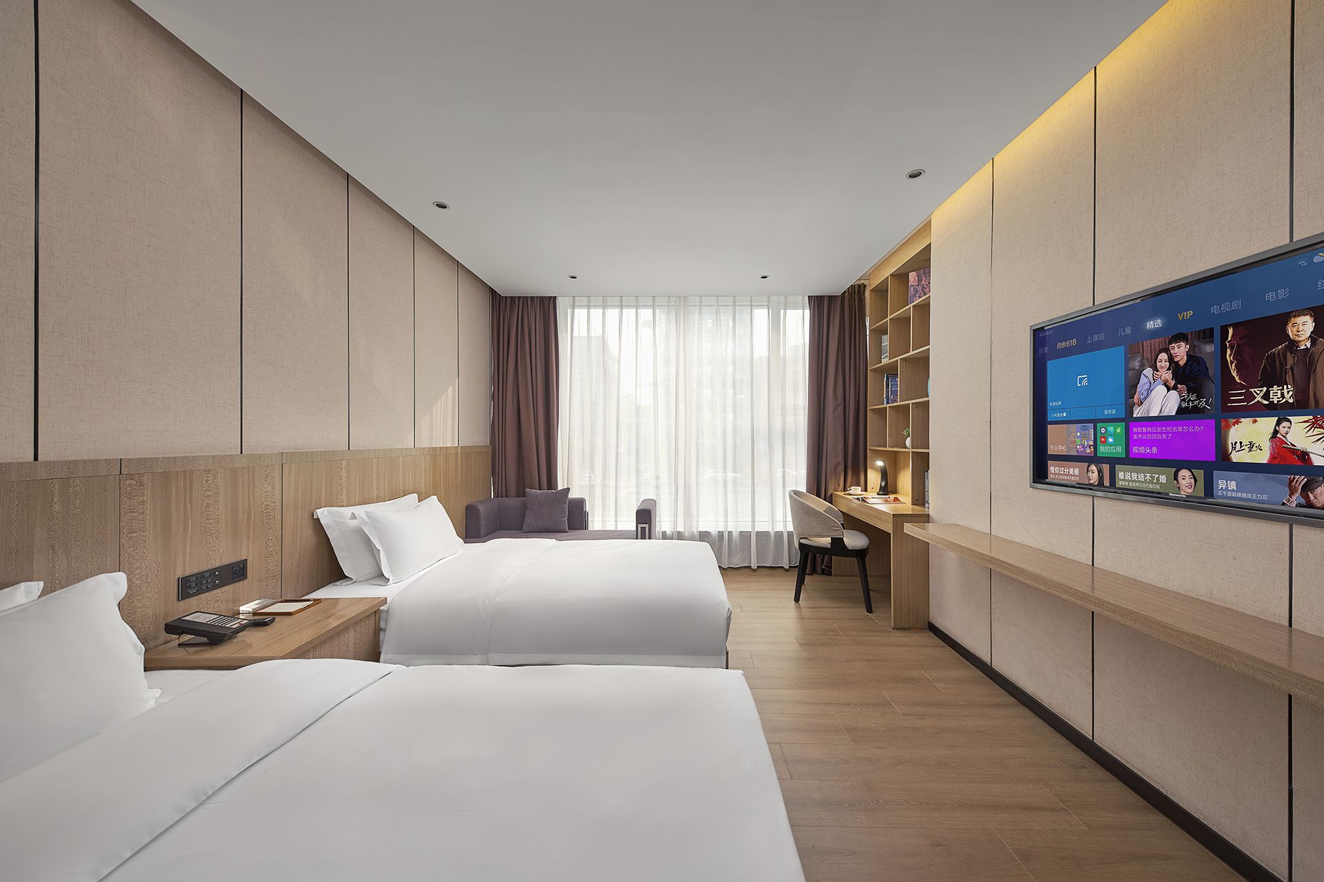 Ein Hotelzimmer mit zwei Betten, einem Schreibtisch, einem Sessel, einem Fernseher und einem Bücherregal.