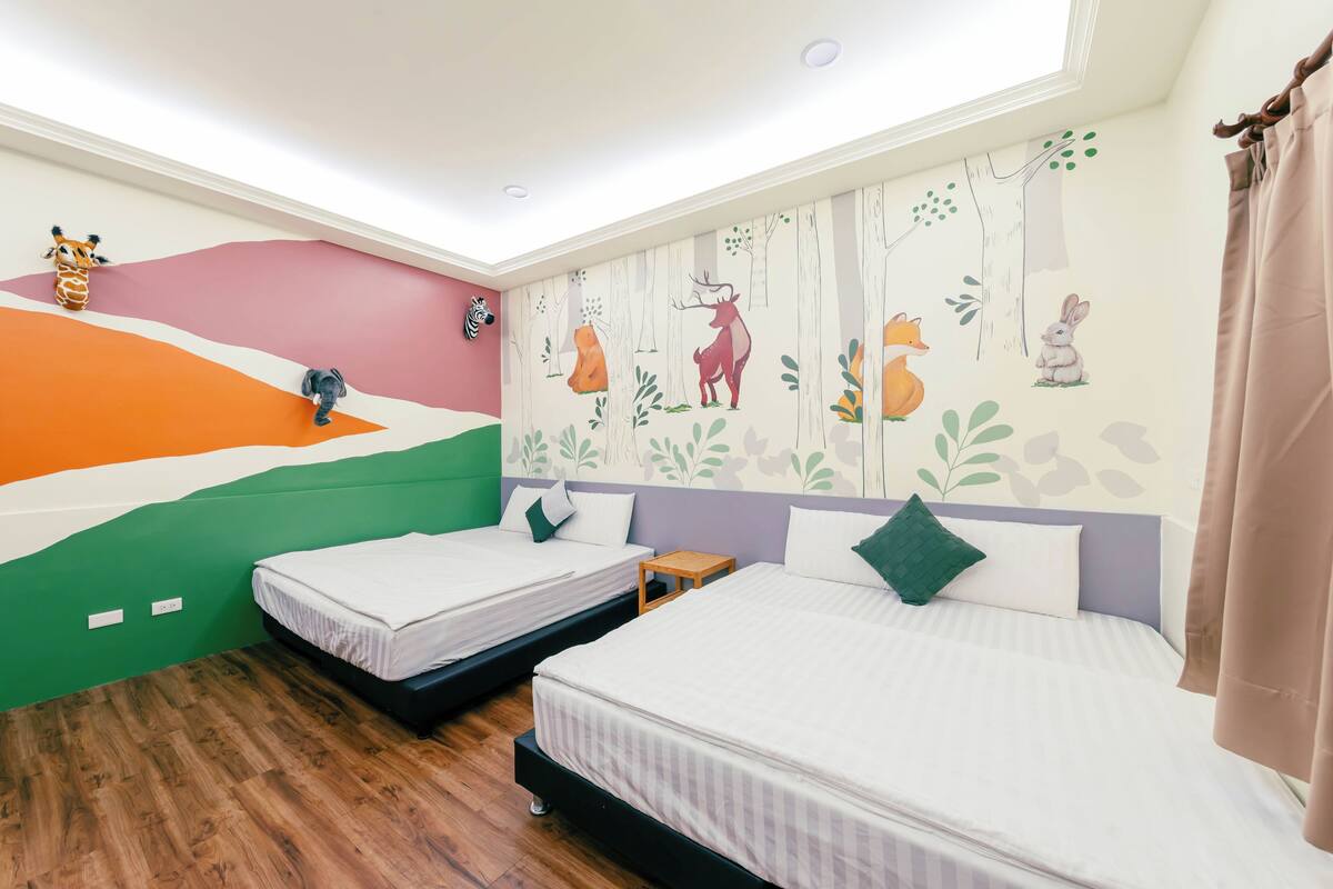 A room with two beds, a mural with animal and tree designs, a zebra head sculpture, and a wooden floor.