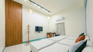 A hotel room with a wooden door, a TV, a desk, two beds with pillows, and a ceiling light fixture. - Mugang Retreat｜Liuqiu Kids' Playroom (Liuqiu)