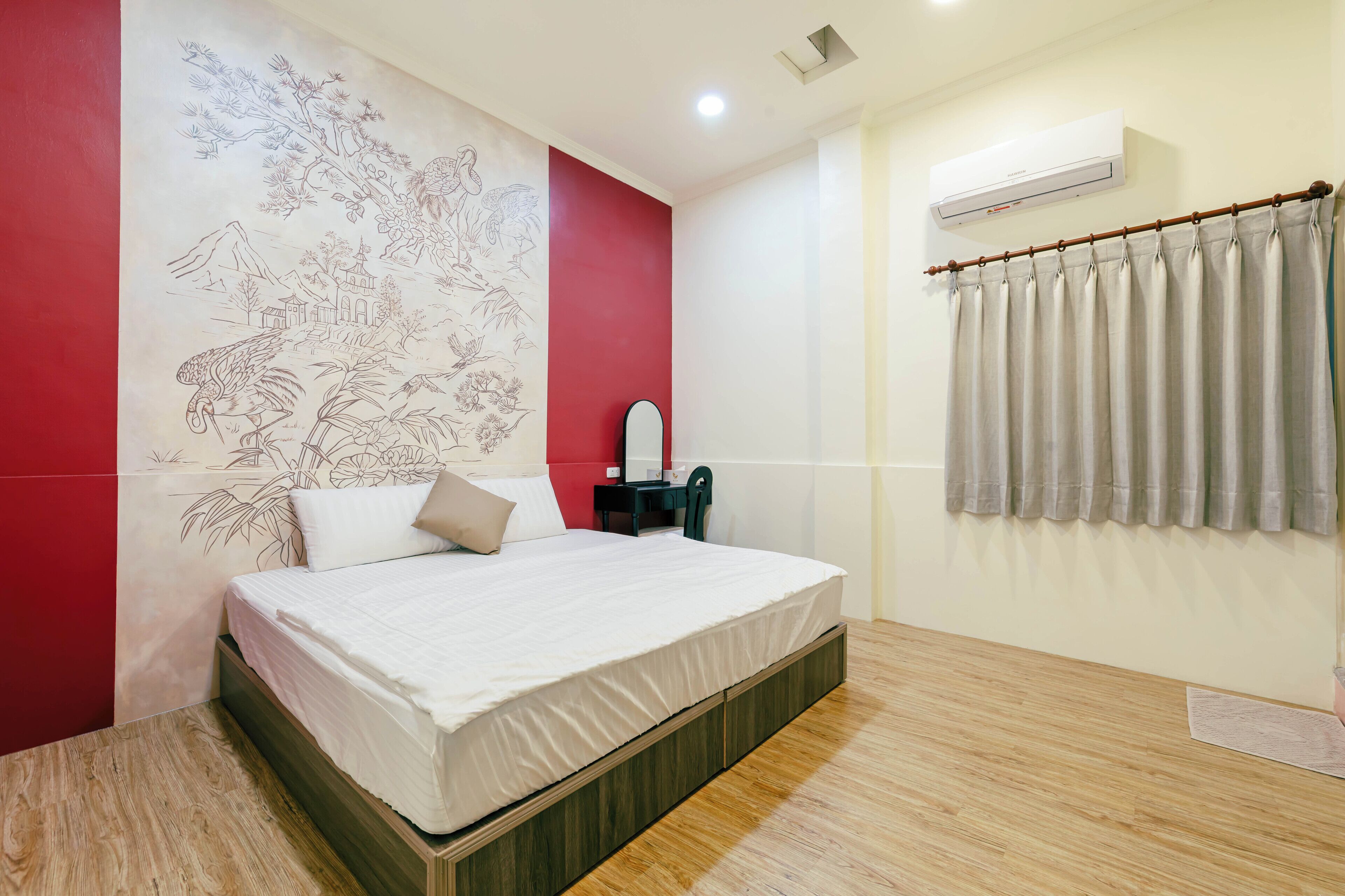 A bedroom with a bed, a nightstand, a mirror, and a wall-mounted air conditioner.