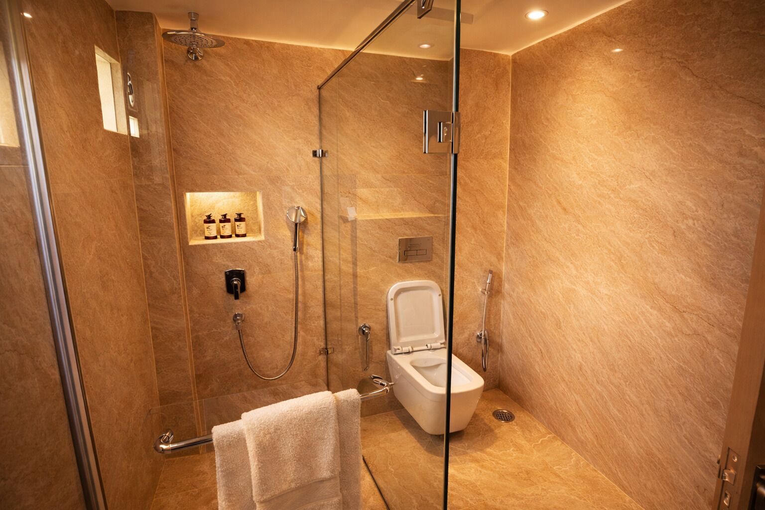 A modern bathroom with a glass-enclosed shower, a toilet, and a towel rack.