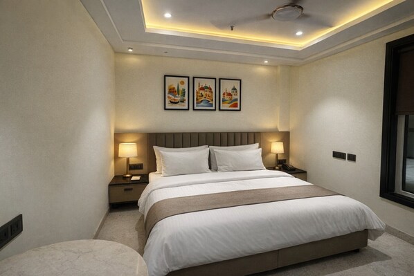 Habitación de hotel moderna con una cama grande, dos mesitas de noche con lámparas, una lámpara de techo y tres cuadros en la pared.