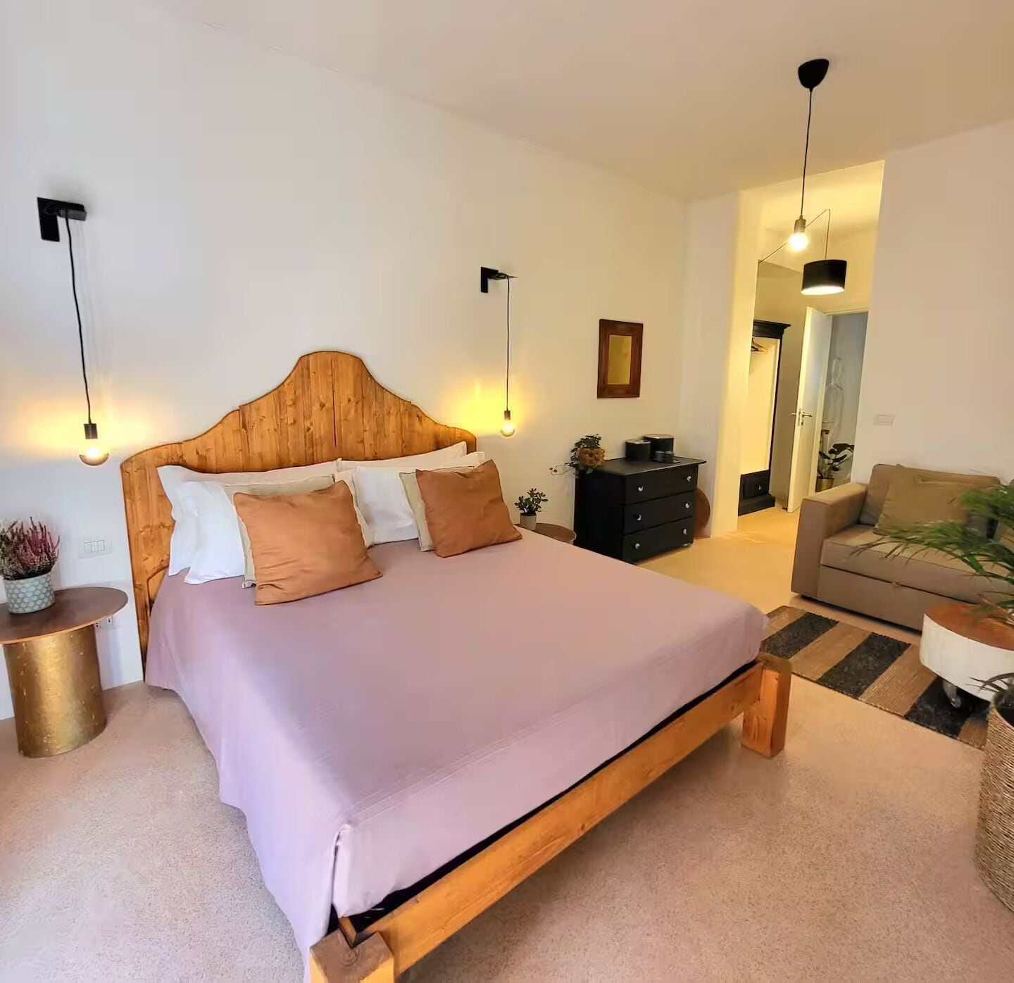 A bedroom with a wooden bed, a bedside table, a dresser, and a sofa.