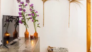 Une pièce avec un bureau en béton, deux fleurs violettes dans des vases marron, un panier tressé et un élément décoratif fixé au mur.