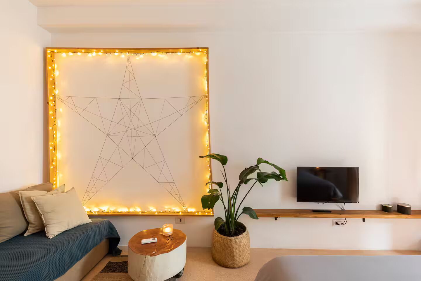 Una sala de estar moderna con una obra de arte grande montada en la pared, un televisor, un sofá, una mesita auxiliar y una planta en maceta.