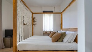 Une chambre à coucher avec un lit à baldaquin en bois, une télévision, une fenêtre avec des rideaux et une petite étagère ornée d’objets décoratifs.