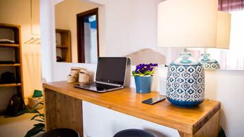 A wooden desk with a laptop, a smartphone, a potted plant, and a patterned lamp.