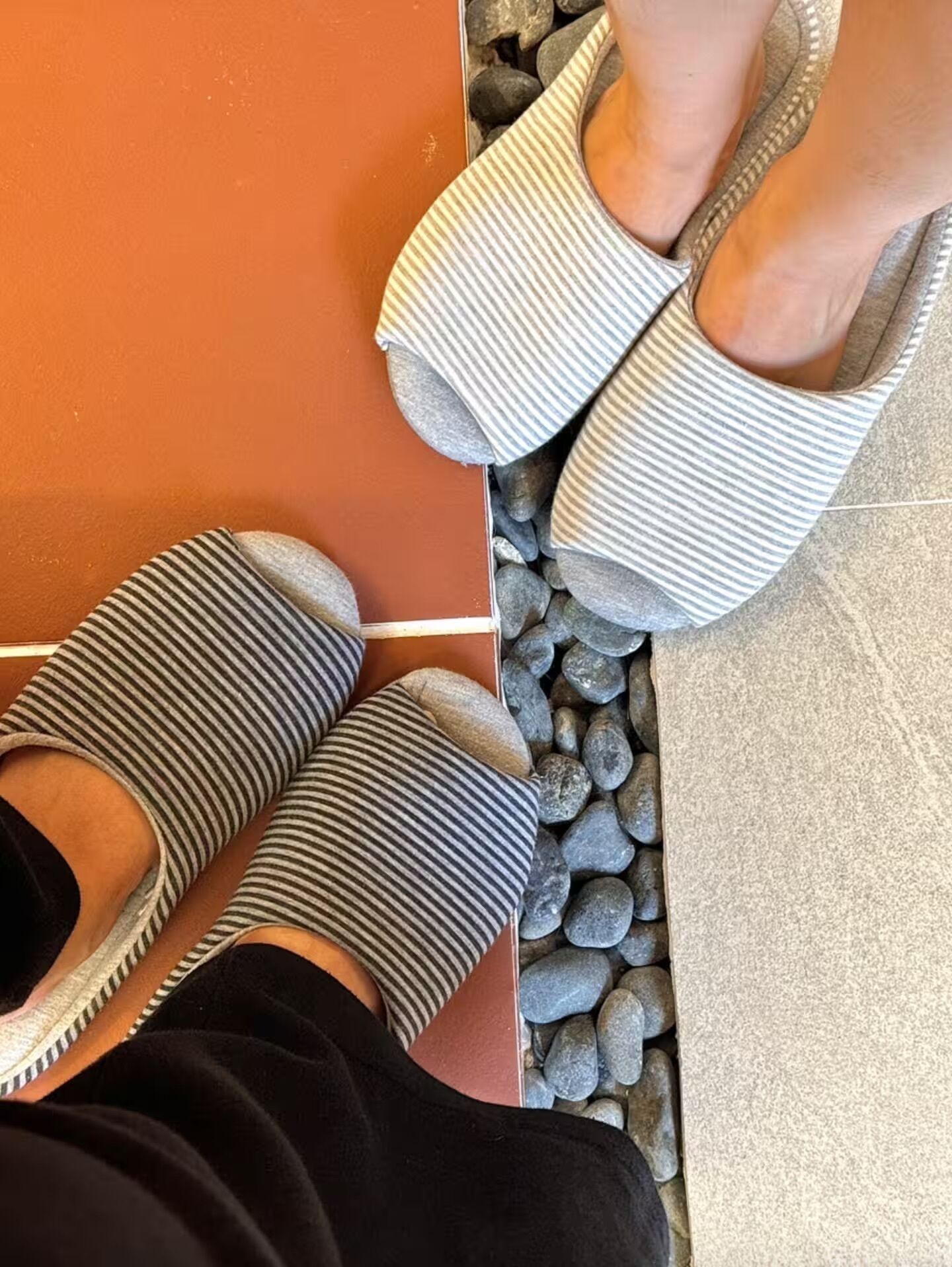 Primer plano de pantuflas a rayas sobre un suelo de baldosas.