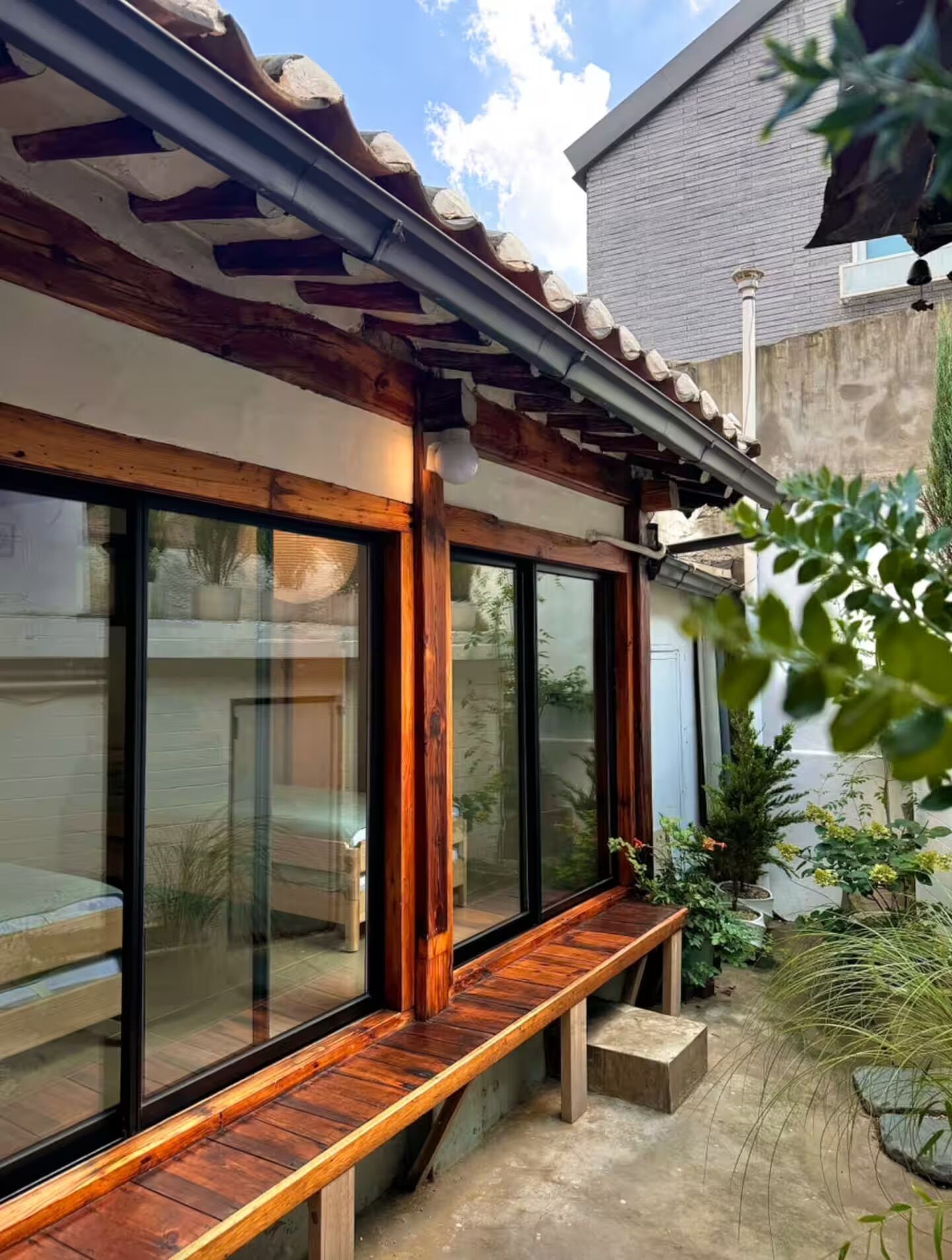 A modern house with large glass windows, a wooden deck, and a stone wall.