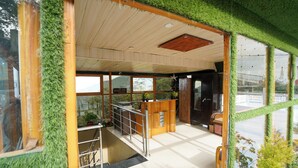 Un intérieur moderne avec un comptoir d’accueil en bois, un escalier et de grandes fenêtres offrant une vue sur l’extérieur.