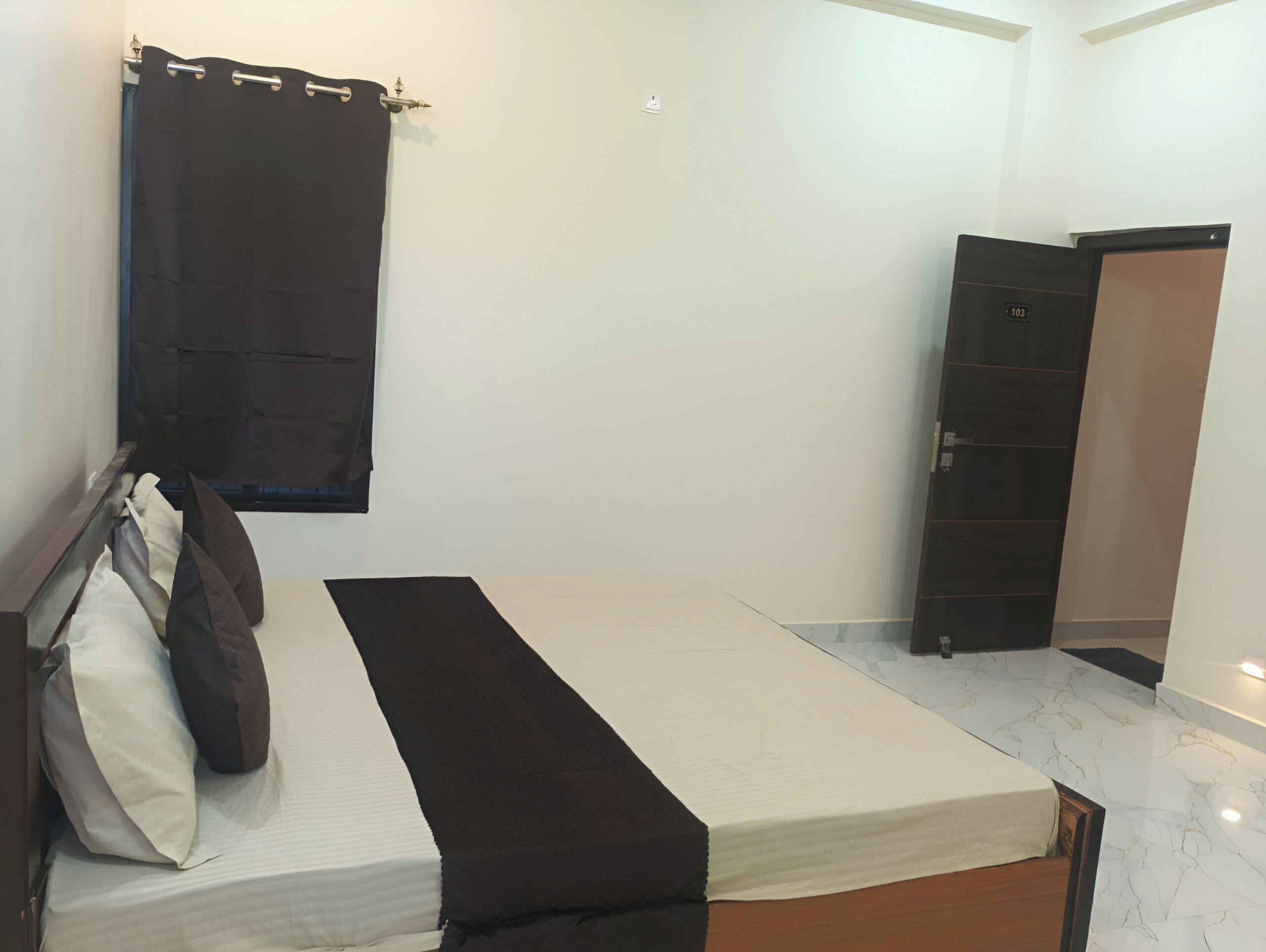 A bedroom with a bed, a dark curtain, a wardrobe, and a tiled floor.