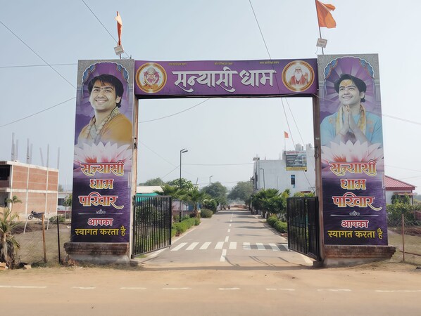 A gate with a signboard displaying text in a non-English script, flanked by two pillars with images and text.