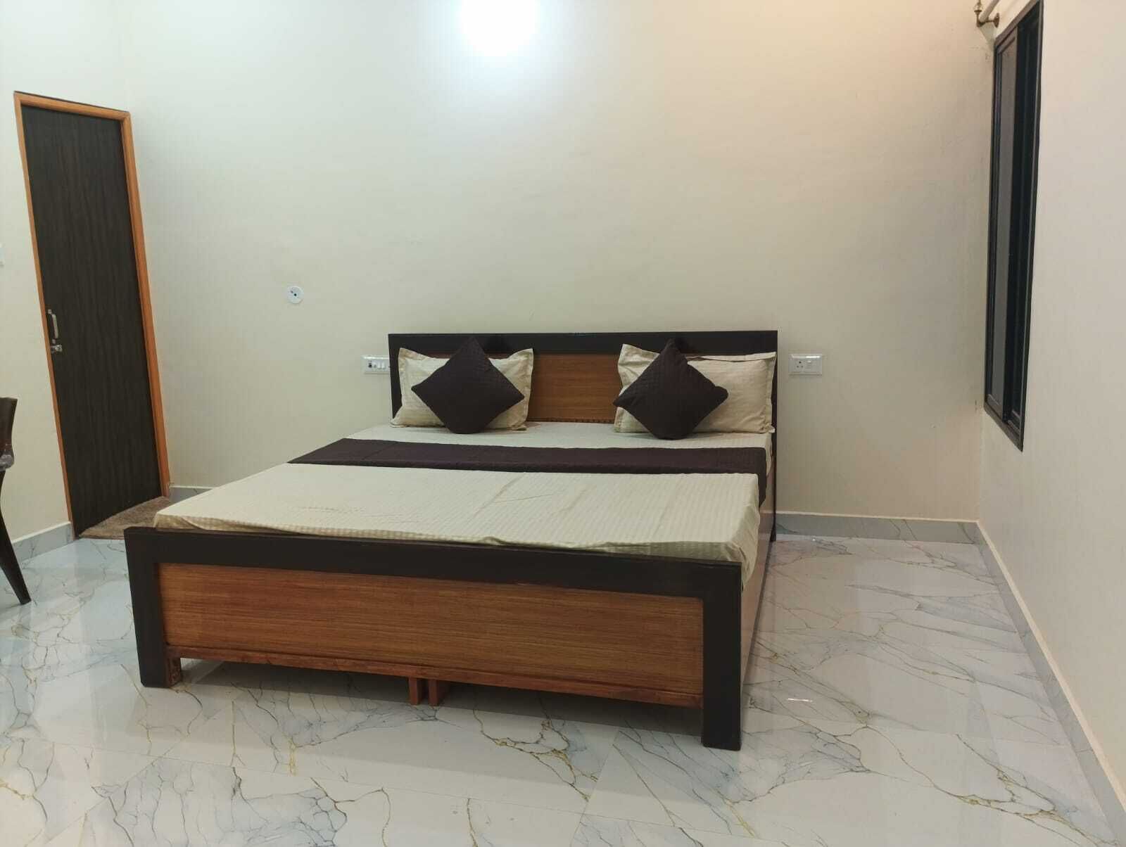 Un dormitorio con una cama, una puerta y una lámpara fijada a la pared.