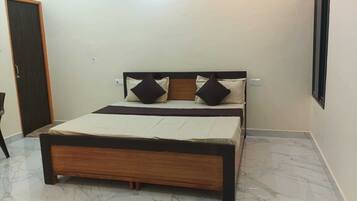 Un dormitorio con una cama, una puerta y una lámpara fijada a la pared.