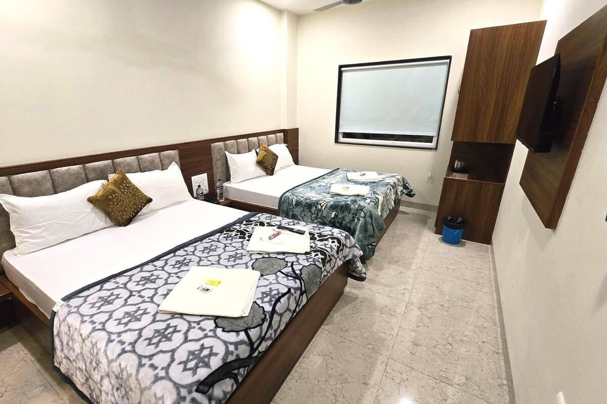A hotel room with two beds, a TV, and a minibar.