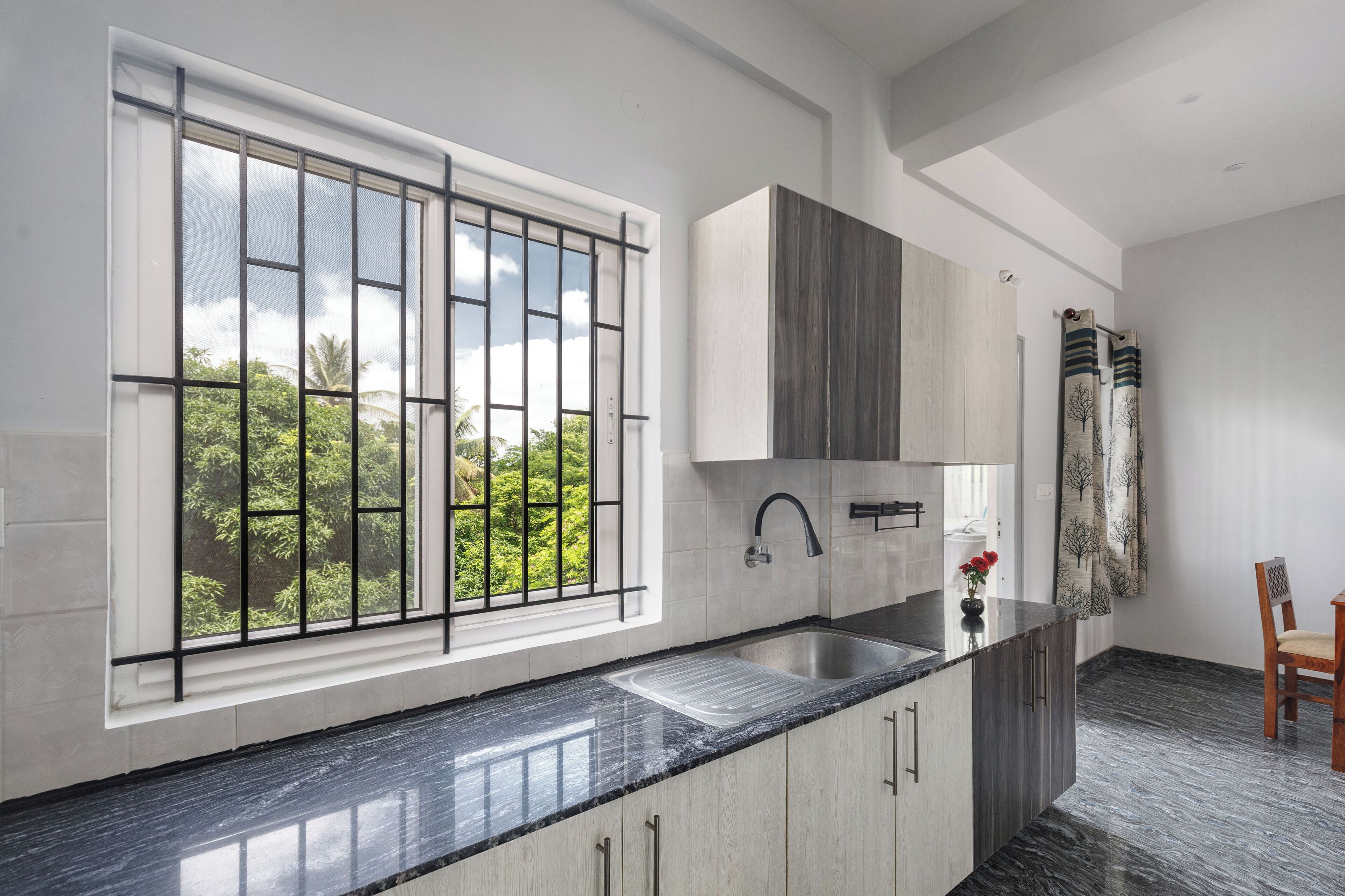 A modern kitchen with a large window, a sink, and a chair.