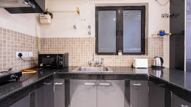 Una cocina con encimera negra, un fregadero, una ventana y un microondas.