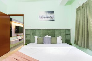 A bedroom with a bed, a headboard, a painting, a television, and a bathroom visible through an open door. - Serenity Green by Jadecaps 3bhk South Kolkata (Kolkata)