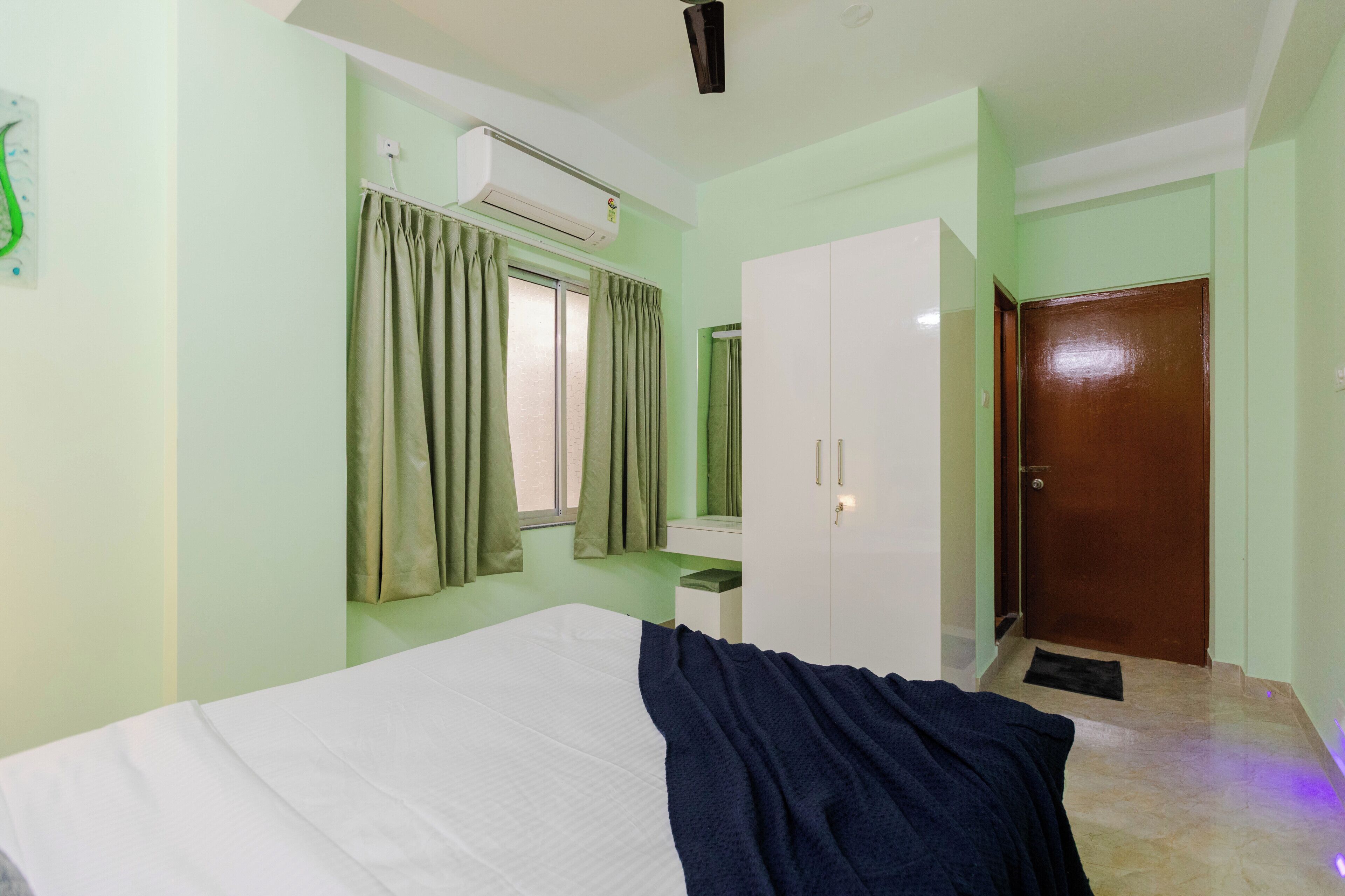 Une chambre à coucher comprenant un lit, un appareil de climatisation, une armoire, un miroir et une porte.