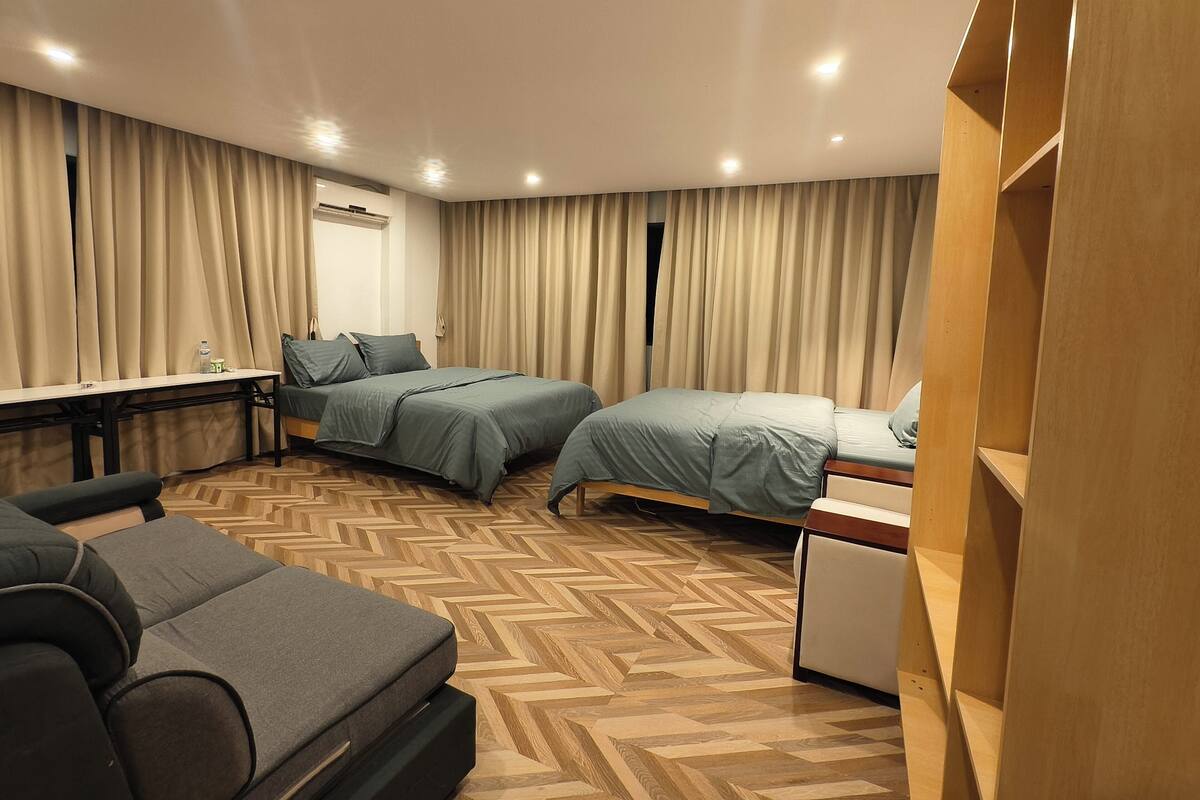 A hotel room with two beds, a desk, a chair, and a wardrobe.
