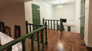 Un escalier avec des marches en bois et des rampes vertes menant à un palier doté d’une porte verte et d’un luminaire.