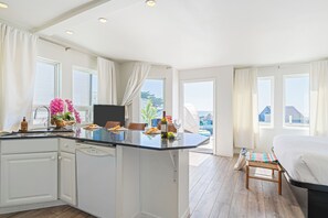 Una cocina moderna con una isla central, armarios blancos y una zona de comedor con banco.