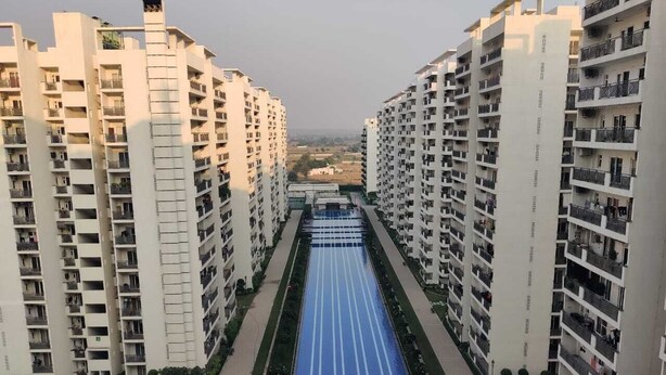 Un conjunto de edificios residenciales altos con varios balcones y un sendero central azul.