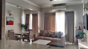 Una sala de estar moderna con un sofá, una mesa de comedor con sillas, un televisor y un ventilador de techo.