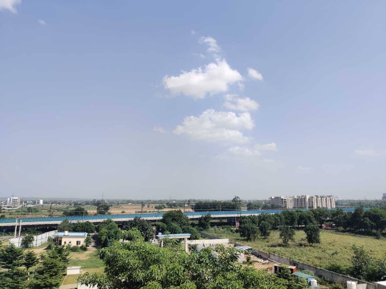 A view of a residential area with buildings, greenery, and a clear sky.