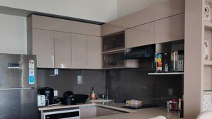 Una cocina moderna con una isla central, dos taburetes de bar, electrodomésticos de acero inoxidable y salpicadero.