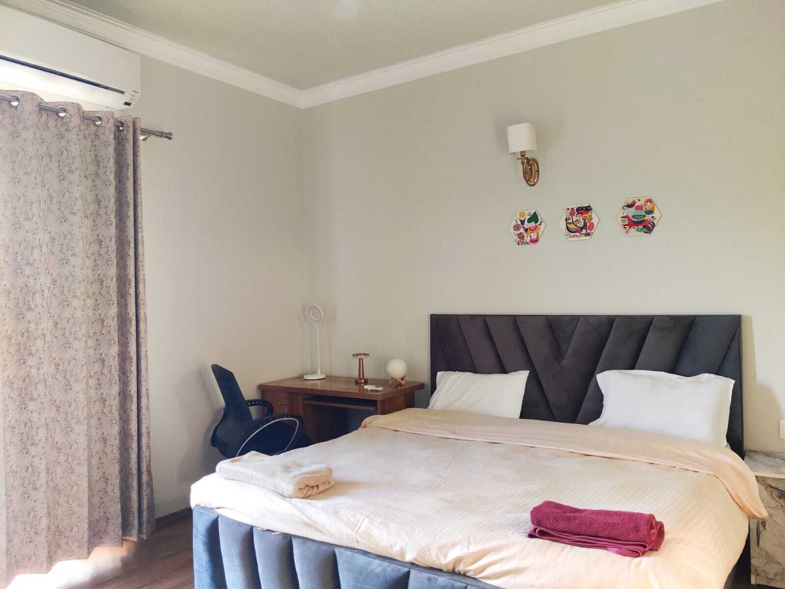 Ein Hotelzimmer mit einem Bett, einem Schreibtisch, einem Stuhl und einer Wandlampe.