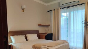 Una cama bien hecha con una colcha color beige, un cabecero de madera y una mesita de noche con una lámpara.