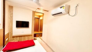 Ein kompaktes Hotelzimmer mit Bett, Wand-Fernseher, integriertem Kleiderschrank und Klimaanlage.