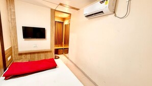 Ein Hotelzimmer mit Bett, einem an der Wand montierten Fernseher, einer Klimaanlage und einer Wandverkleidung aus Holz.