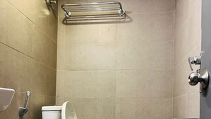 Une petite salle de bain carrelée, équipée de toilettes, d’un bidet et d’une douche.