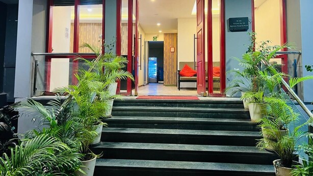 L’entrée d’un hôtel, avec un escalier, des plantes en pot et un espace d’accueil.