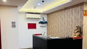 Un espace d’accueil avec un comptoir noir, une enseigne rouge et un luminaire au plafond.
