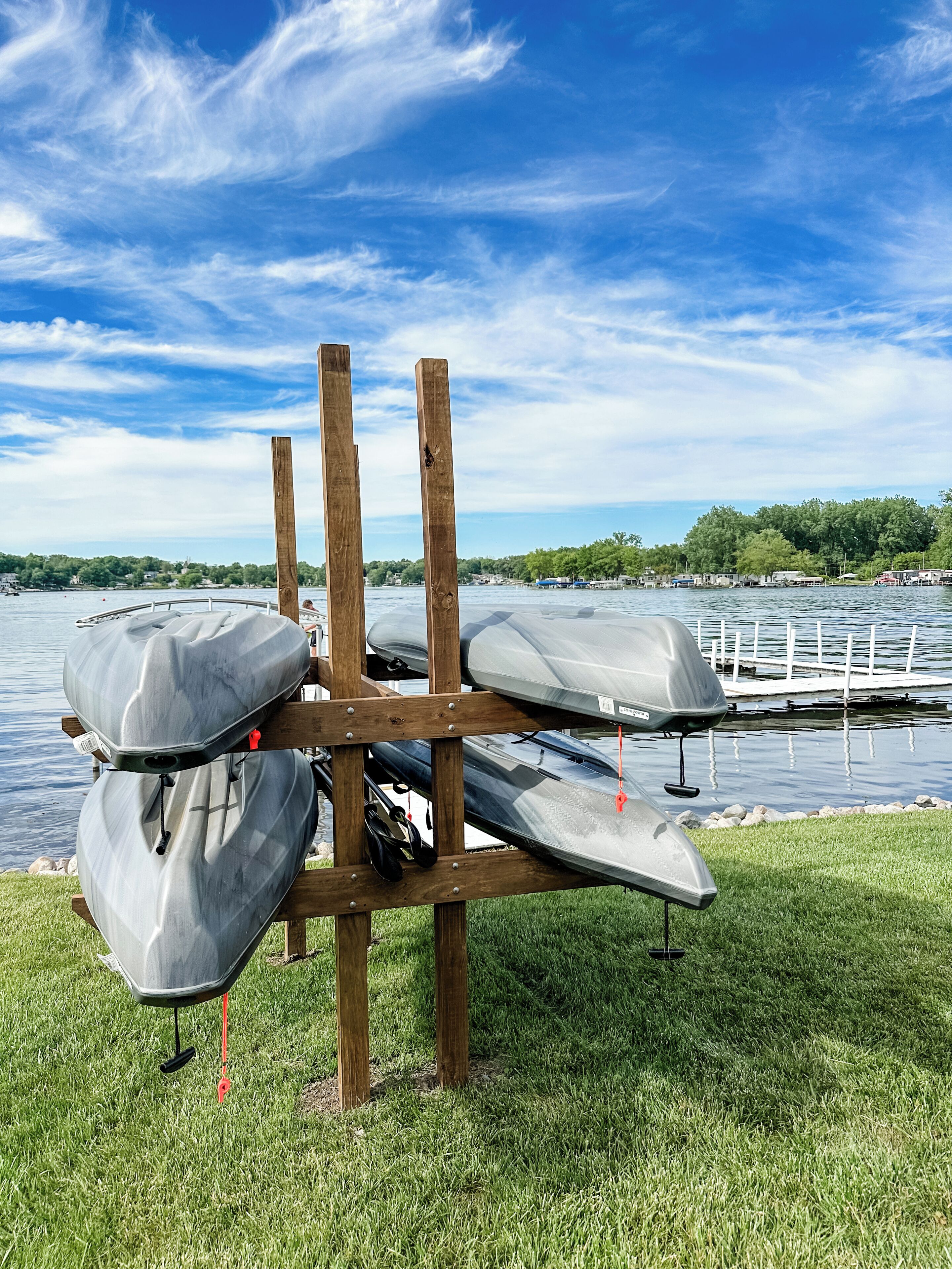 A wooden rack holding kayaks by a lakeside.