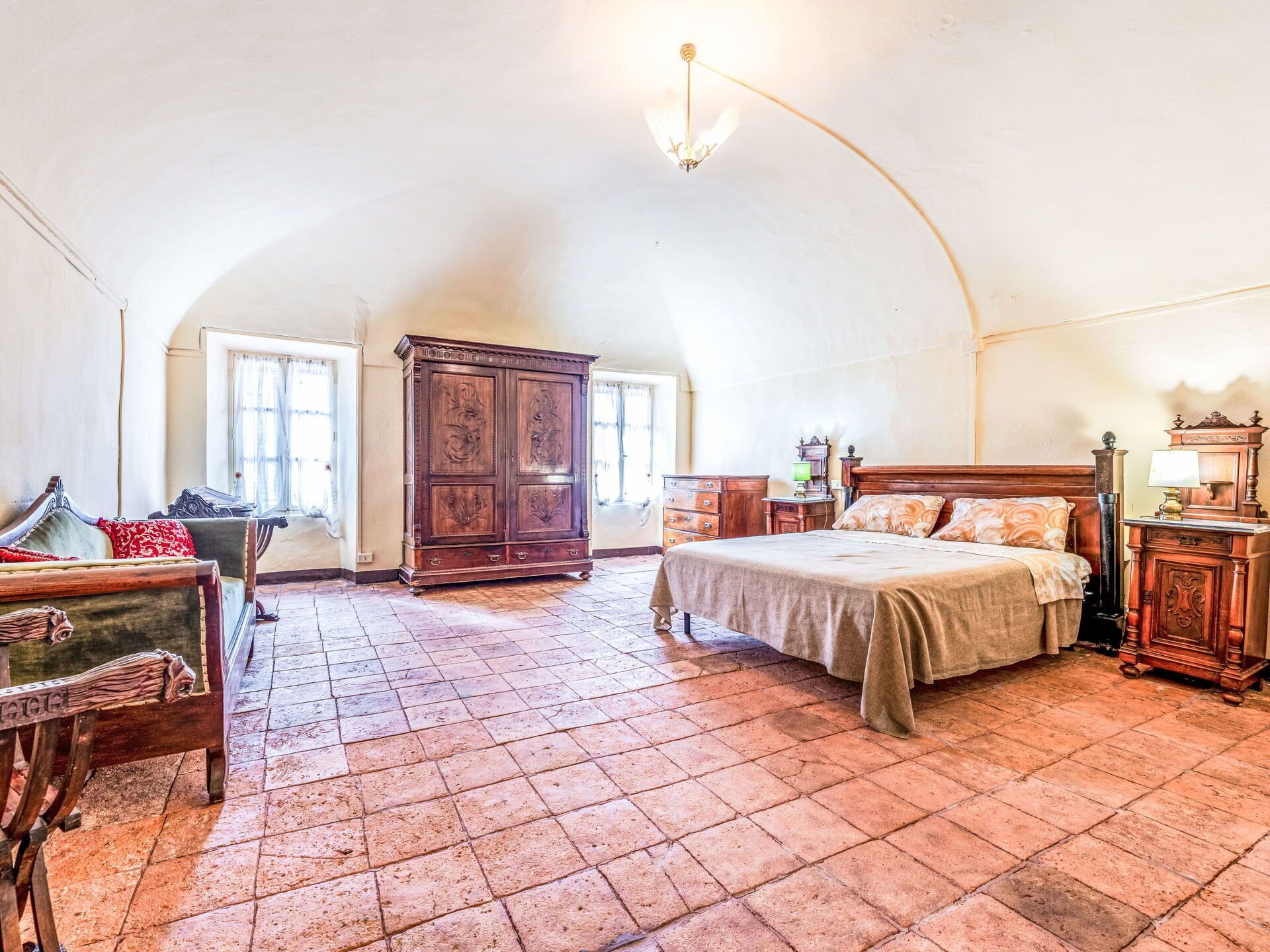 A spacious bedroom with a large bed, a wardrobe, and a chair.