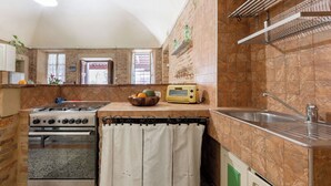 Cocina compacta con estufa a gas, horno y un pequeño mostrador con tostadora.