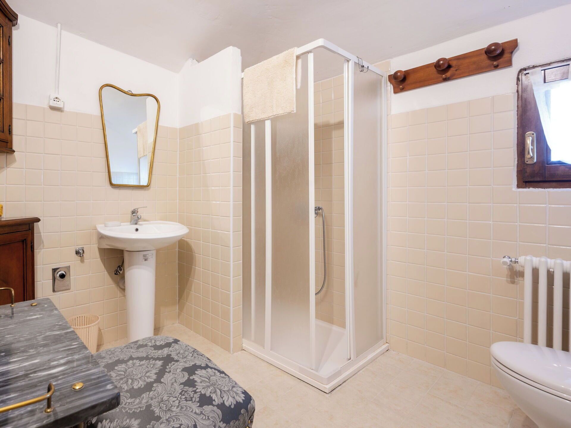 A bathroom with a shower, sink, toilet, and a mirror.