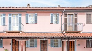 Un edificio rosa con techo de tejas, puertas de madera y contraventanas.