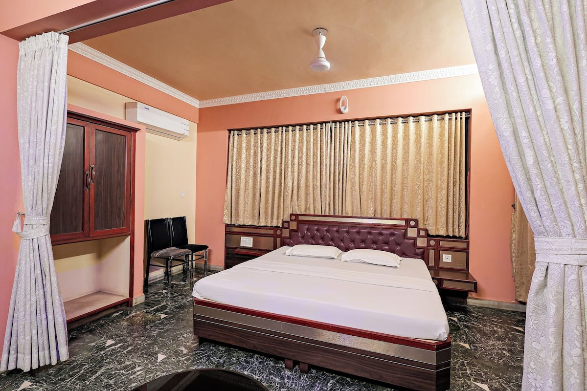 A bedroom with a bed, a wardrobe, a chair, and a ceiling fan.